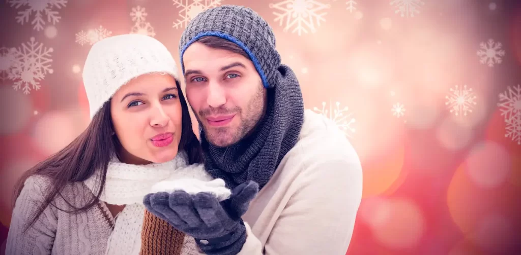 Koppel in winterkleding met sneeuwvlokken op achtergrond.